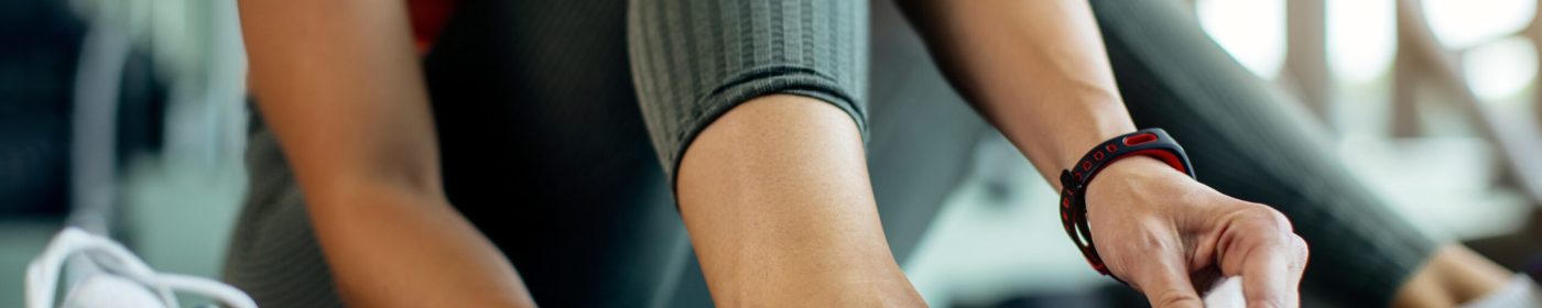 Close-up of female athlete holding her ankle in pain after exercising in health club.